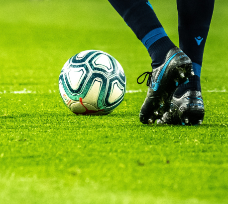 芝生の上でサッカーボールとスパイクを履いた足が写っている写真